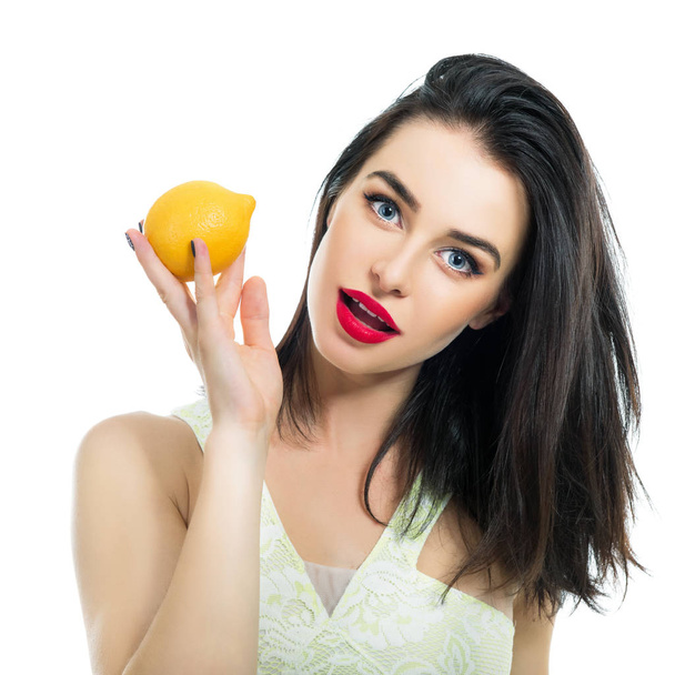 Excited beautiful girl holding lemon and posing in studio over w - Фото, изображение