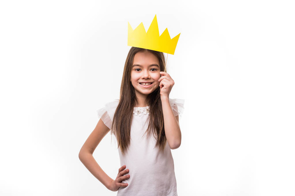 Close up portrait of smiley little girl wearing paper crown isolated on white - Photo, Image