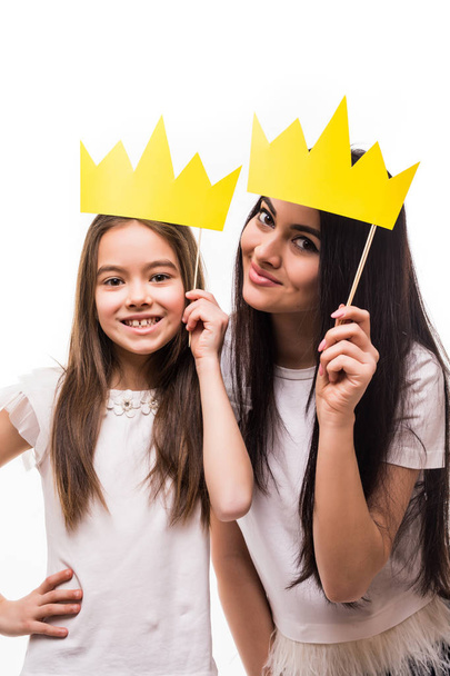 Smiling Mother and daughter posing with paper crowns on stick isolated on white background - Zdjęcie, obraz
