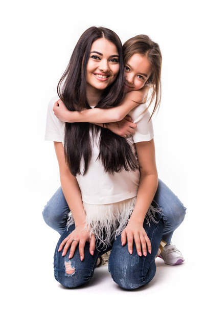 Pequeña hija abrazar a su madre piggyback aislado sobre fondo blanco
 - Foto, imagen