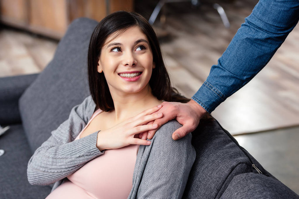 Schnappschuss einer lächelnden jungen Schwangeren, die ihren Mann zu Hause ansieht - Foto, Bild