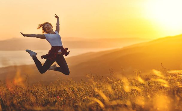 Onnellinen nainen hyppääminen ja nauttia elämästä auringonlaskun vuoristossa
 - Valokuva, kuva
