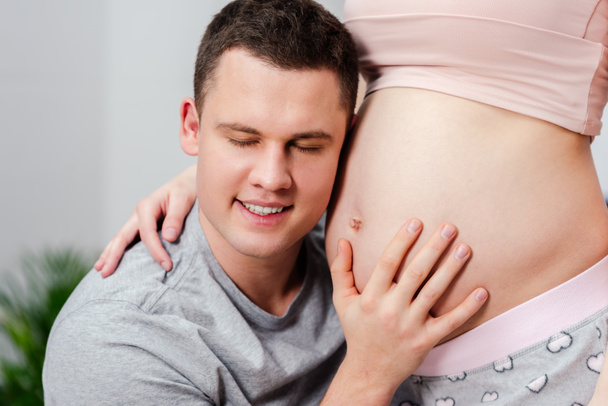 Oříznout záběr šťastný člověk poslouchá břicho těhotné ženy - Fotografie, Obrázek