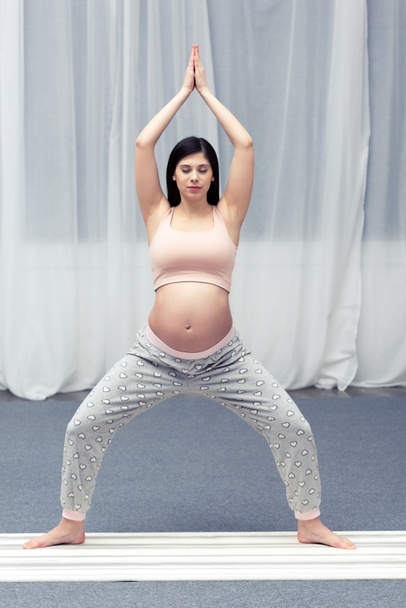 young pregnant woman practicing yoga at home  - Фото, зображення