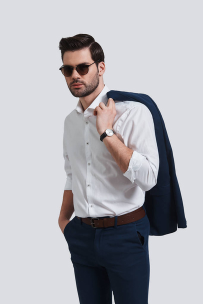 young man keeping hand in pocket and carrying jacket on shoulder - Foto, imagen
