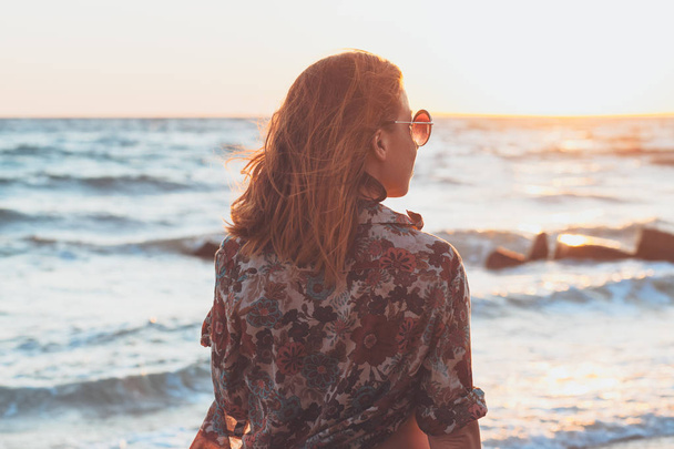 Młoda kobieta korzystających z zachodu słońca i fale na plaży - Zdjęcie, obraz