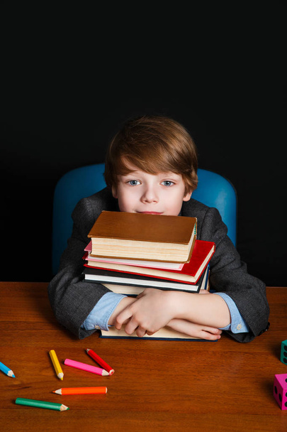 cute boy with books and sitting at a school desk . Back to school. Education - Zdjęcie, obraz