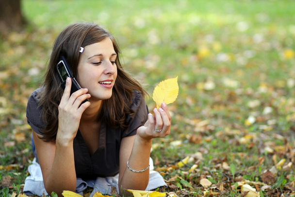 woman calling by phone in autumn park - 写真・画像