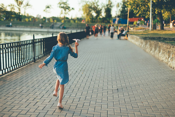 Девушка играет, бегает с игрушечным бумажным самолетом
  - Фото, изображение