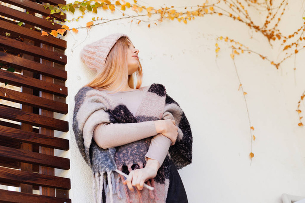 girl  on her shoulders a warm scarf walks outdoors - Foto, afbeelding