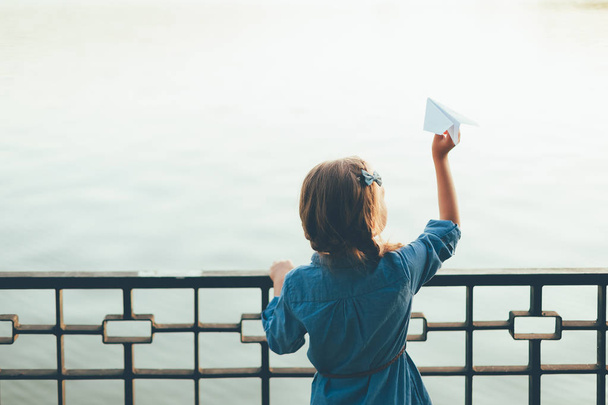 Κορίτσι με το παιχνίδι αεροπλάνο χαρτί ψάχνει στη λίμνη - Φωτογραφία, εικόνα