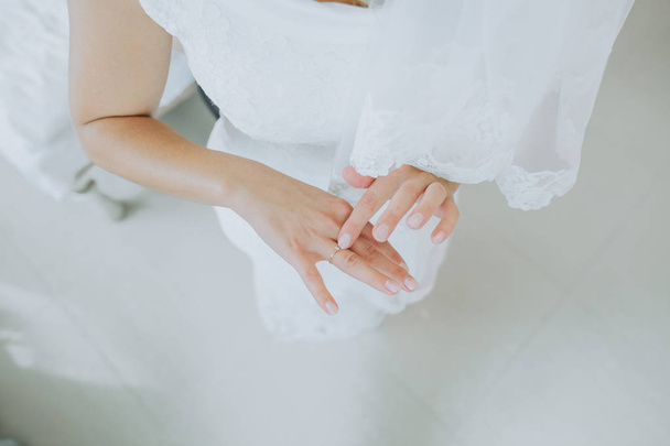 hands bride ring  finger folded against white wedding dress - Foto, afbeelding
