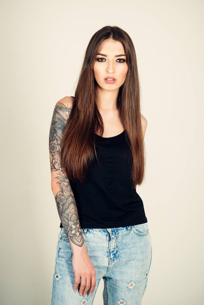 Woman with tattoo arm in jeans, fashion. - Фото, изображение
