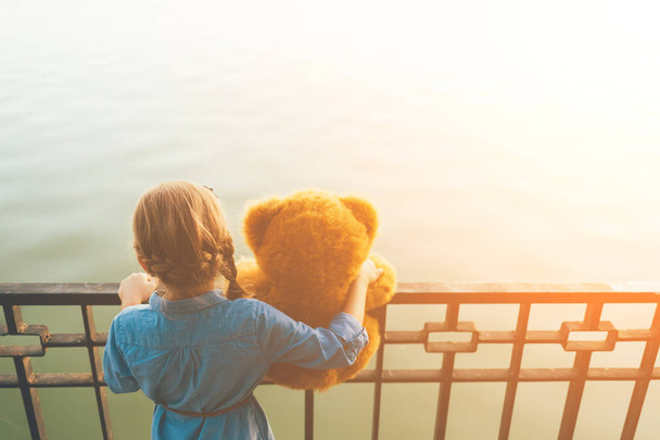 Dívka objímá roztomilý teddy bear, při pohledu na vodu - Fotografie, Obrázek