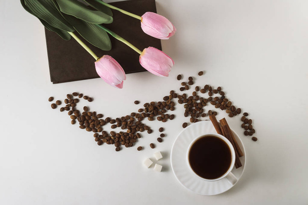 White Cup with Coffee, Coffee Beans, Tulips on a Book on a White - Фото, изображение
