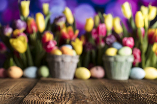 Easter theme. Bouquet of tulips. Easter eggs. Colorful bokeh, place for typography and logo. Rustic wooden table.  - Fotografie, Obrázek