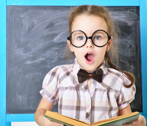Cute liitle girl standing near blackboard in funny big glasses a - Photo, Image