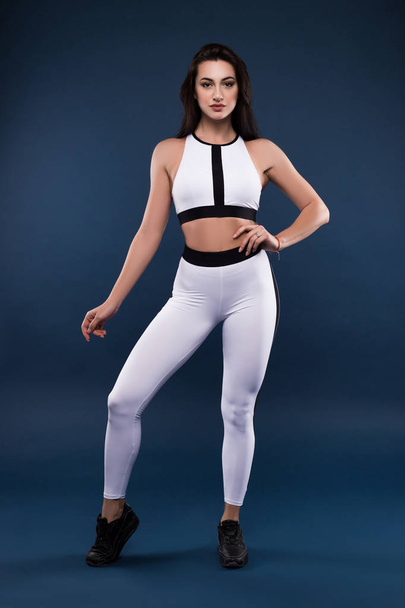 Dreams do not work unless you do! Attractive young graceful sporty brunette posing full length for the professional photo isolated against the dark background. - Fotó, kép