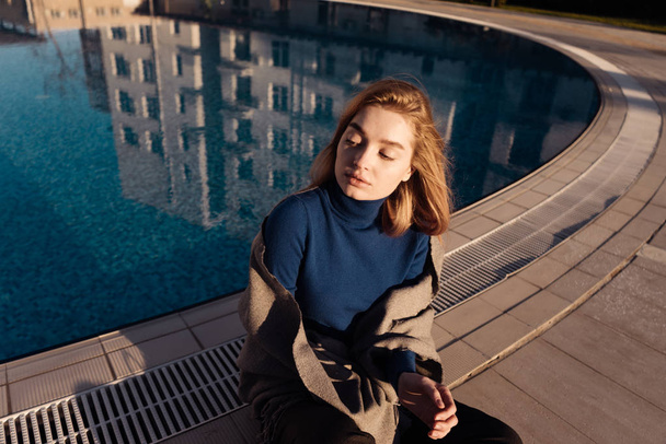 girl sits by the pool, enjoys the sun,eyes closed - Фото, зображення