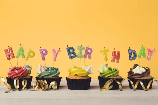 Cupcakes met kaarsen spelling van het woord gelukkige verjaardag - Foto, afbeelding