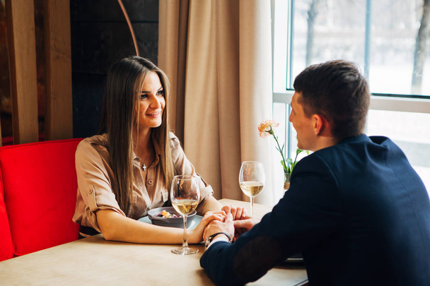 Young happy couple romantic date drink glass of white wine at restaurant, celebrating valentine day - Foto, Imagem