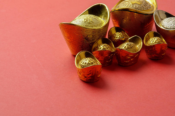 Gold ingots for Chinese New Year festive decorations on a red background. Chinese character means luck,wealth and prosperity as seen in the image. - 写真・画像