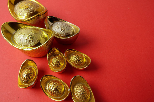 赤の背景に中国の旧正月のお祝いデコレーション用ゴールド地金。中国語の文字を意味する幸運、富と繁栄の画像で見ると. - 写真・画像