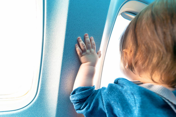 Toddler boy looking out a plane window - Фото, изображение