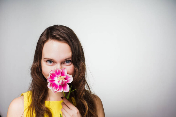 blue-eyed girl sniffs a fragrant pink flower - Фото, зображення