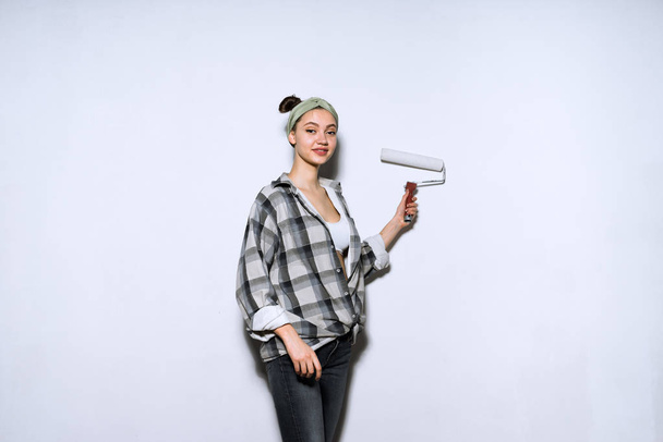 woman  doing repairs, paints a wall with a roller - Foto, Bild