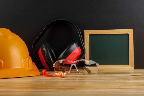 HEALTH AND SAFETY CONCEPT. Personal protective equipment on wooden table over black background. - Photo, Image