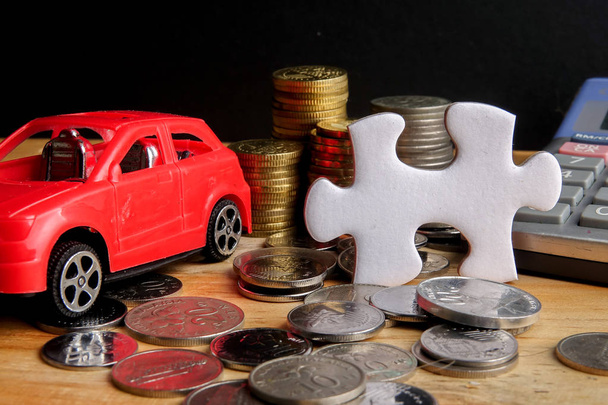 Auto-Finanzierungskonzept: Kleinwagen, Münzen, Puzzleteil und Taschenrechner auf Holztisch. Kopierraum - Foto, Bild