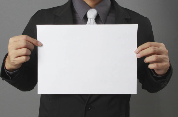 Hand holding white blank paper sheet mockup - 写真・画像