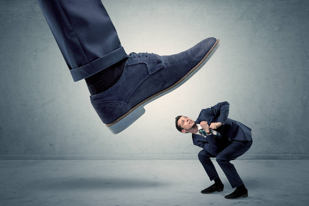 Employee getting trampled by big shoe - Foto, imagen