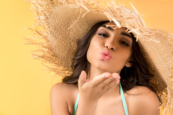 beautiful girl in straw hat blowing kiss, isolated on yellow - Zdjęcie, obraz