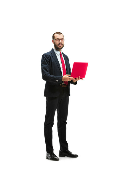 Picture of handsome young bearded man standing over white studio background with laptop - Fotó, kép