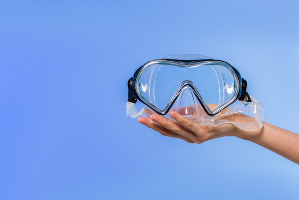 обрезанный вид женской руки с плавательными очками, изолированный на голубом
 - Фото, изображение