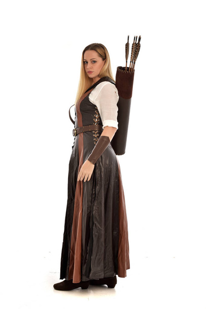 Ganzkörperporträt einer Frau im braunen mittelalterlichen Fantasiekostüm mit Pfeil und Bogen. stehende Pose auf weißem Studiohintergrund. - Foto, Bild