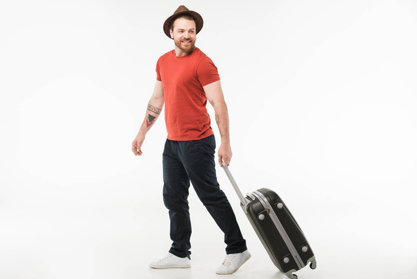 Stylish man in hat carrying suitcase isolated on white, travel concept - Photo, Image