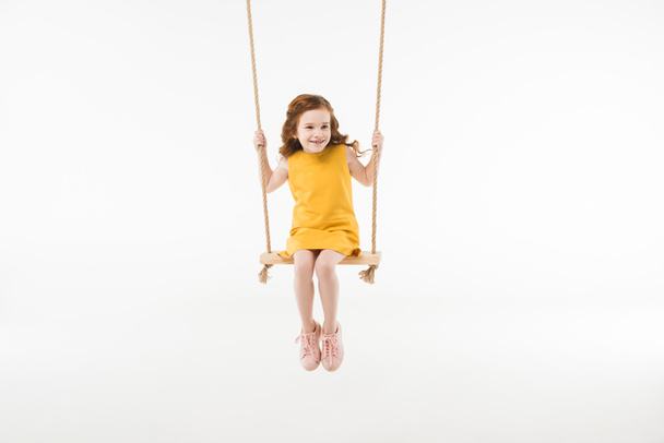 Pequena criança elegante no vestido montando no balanço isolado no branco
 - Foto, Imagem