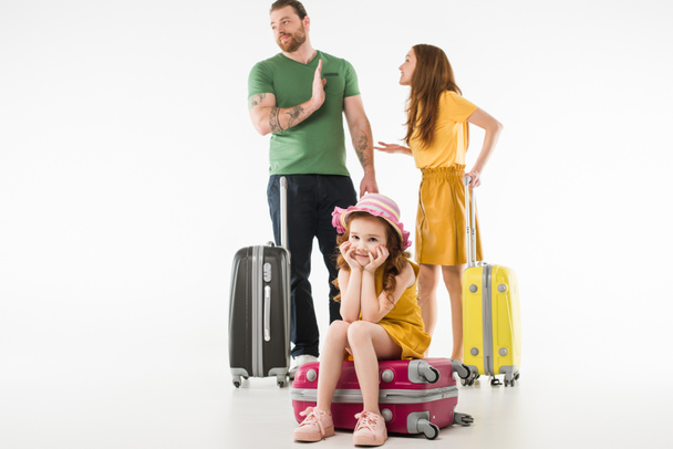 Upset little child sitting on suitcase while parents arguing isolated on white, travel concept - Photo, Image
