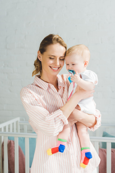 Glimlachend moeder bedrijf dochtertje met baby pop - Foto, afbeelding
