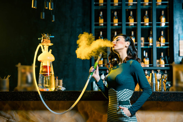 Fiatal nő, dohányzás mögött a bárban egy vízipipa. Felhő füst. Fiatal nő élvezi a vízipipa szépség portréja - Fotó, kép