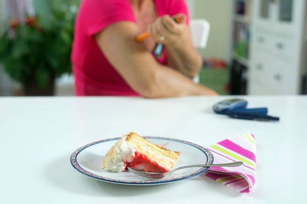 Женщина диабетическая пациентка вколола себе укол инсулина перед тем, как съесть кусок торта для пустыни
. - Фото, изображение