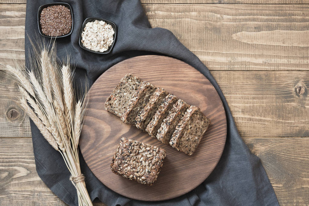 A loaf of fresh rustic whole rye bread on wooden table. Healphy food background. Top view. Copy space. Fitness wholegrain bread. - Foto, Bild