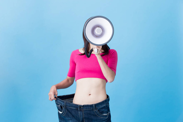 woman with megaphone  showing  weight loss  on the blue background - Foto, immagini