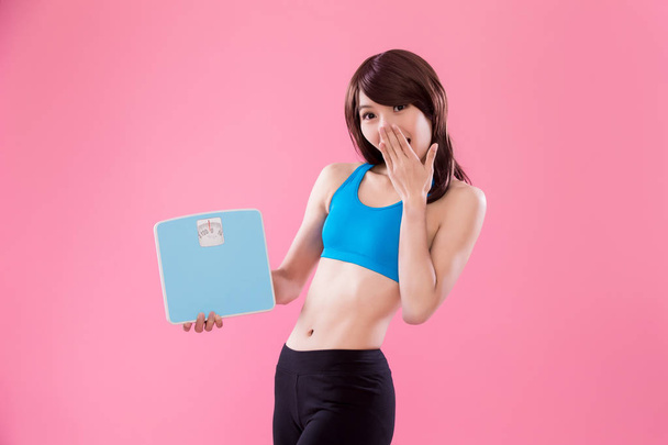 sport woman holding  scales  on the pink background - Photo, image