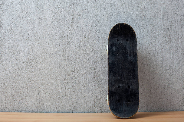 Skateboard standing on a wall. - Foto, Imagen