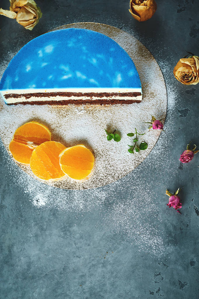 half of cutted mousse cake with blue glaze on a dark gray concrete background - Fotografie, Obrázek