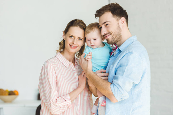 Young smiling family with infant daughter in hands - Photo, Image